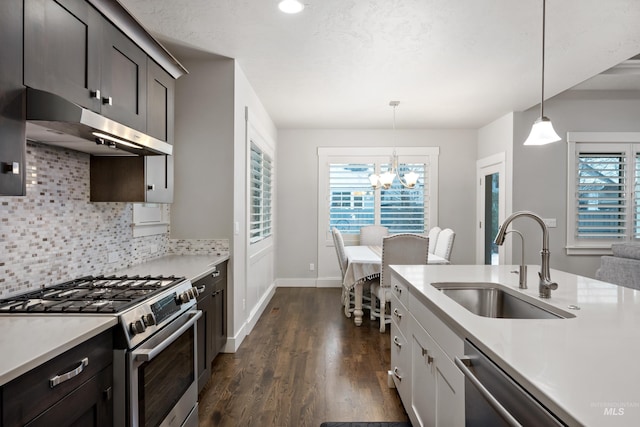 kitchen featuring sink, an inviting chandelier, pendant lighting, decorative backsplash, and appliances with stainless steel finishes