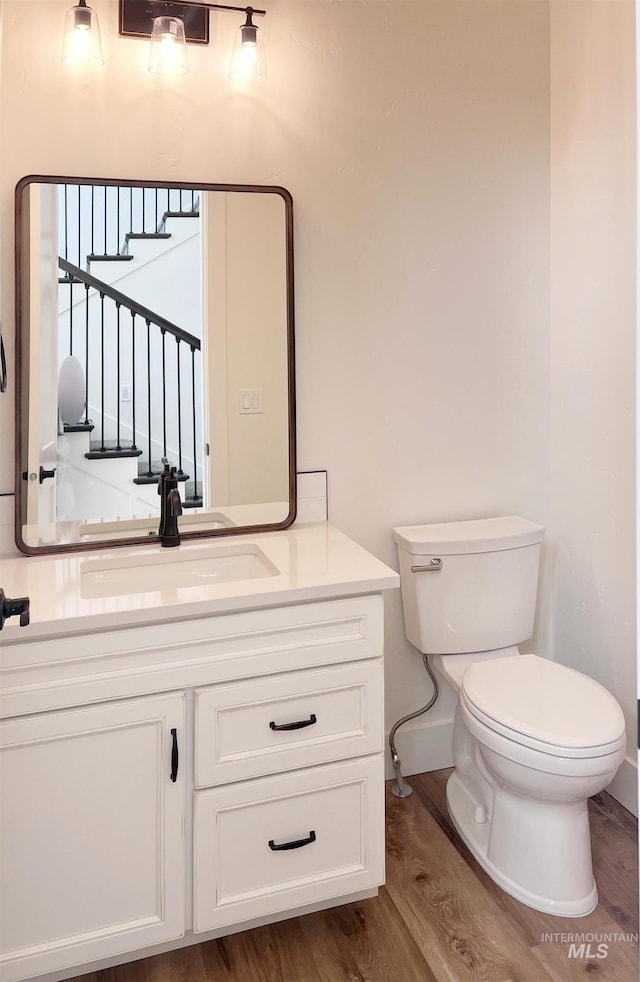 bathroom with wood finished floors, vanity, and toilet