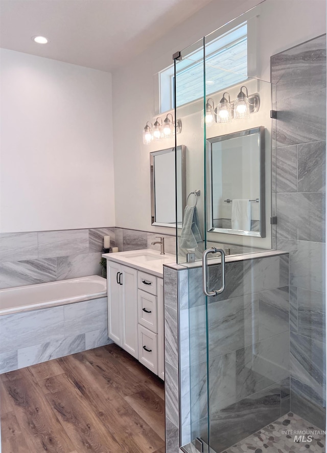 full bathroom with wood finished floors, a stall shower, a garden tub, and vanity