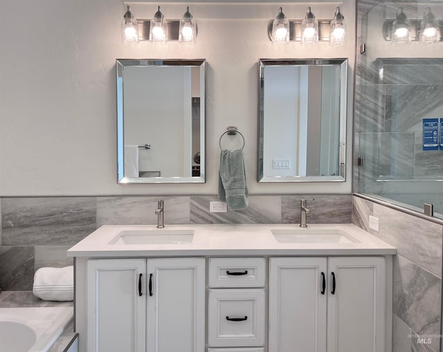 full bath featuring double vanity, a sink, and tile walls