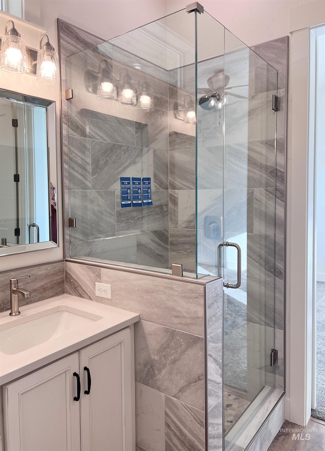 bathroom featuring a ceiling fan, a stall shower, backsplash, and vanity