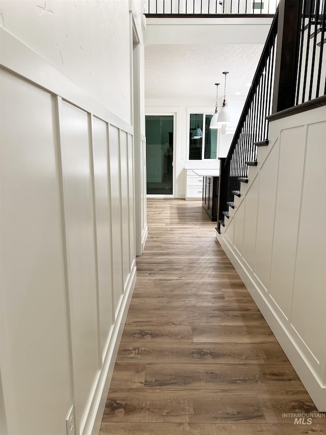 hall featuring stairs, wood finished floors, and a decorative wall