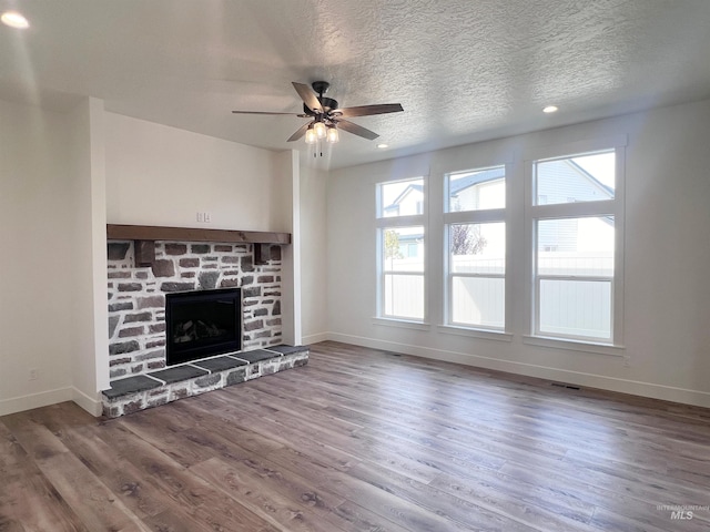 unfurnished living room featuring a stone fireplace, wood finished floors, and baseboards