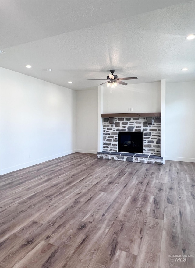 unfurnished living room featuring ceiling fan, a textured ceiling, baseboards, and wood finished floors