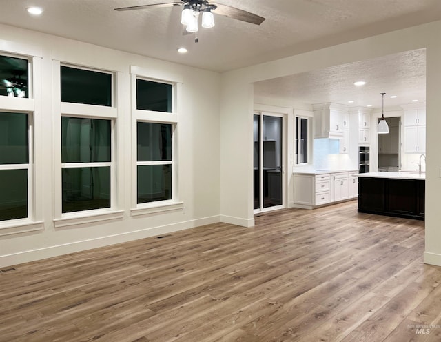 unfurnished living room featuring recessed lighting, ceiling fan, a textured ceiling, light wood-type flooring, and baseboards