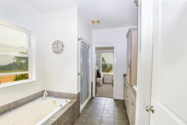 bathroom featuring tiled bath, vanity, tile patterned floors, and plenty of natural light