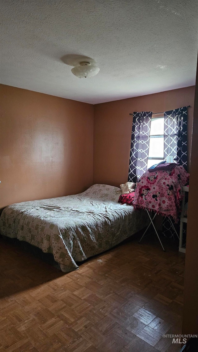 bedroom with dark parquet flooring and a textured ceiling