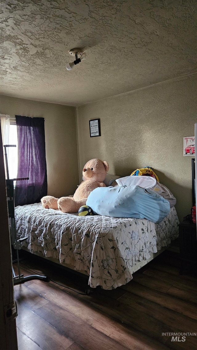 bedroom with a textured ceiling and hardwood / wood-style flooring