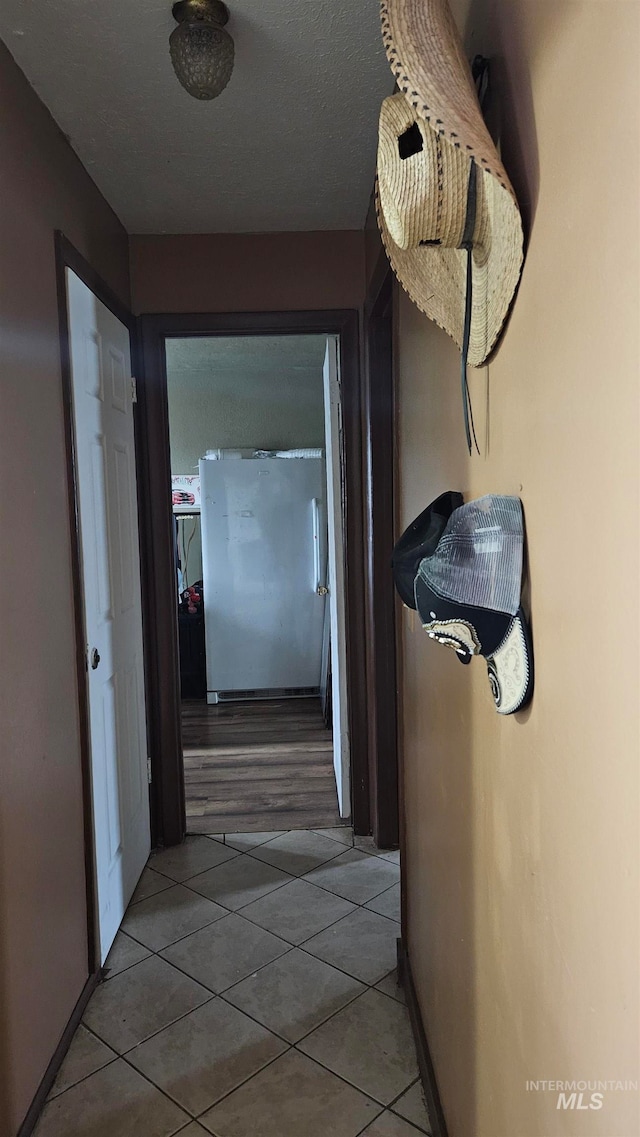 corridor with tile patterned flooring and a textured ceiling