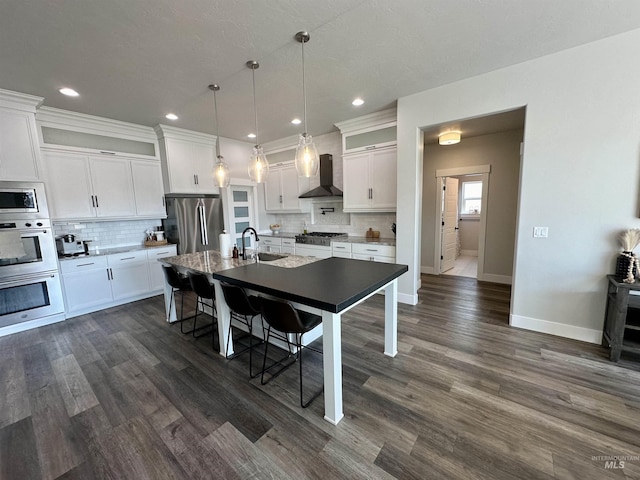 kitchen featuring stainless steel appliances, sink, pendant lighting, a center island with sink, and white cabinetry