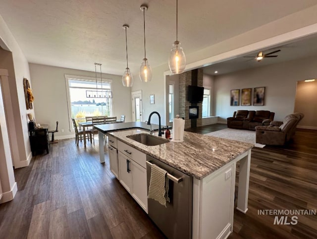 kitchen featuring dishwasher, sink, light stone counters, a center island with sink, and white cabinets