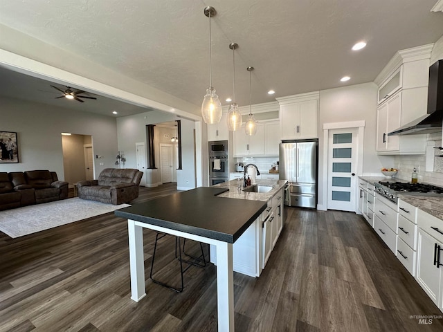 kitchen with sink, stainless steel appliances, tasteful backsplash, decorative light fixtures, and white cabinets