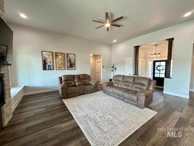 living room featuring a fireplace, ceiling fan with notable chandelier, and dark hardwood / wood-style floors