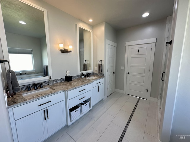 bathroom with a washtub, vanity, and tile patterned floors