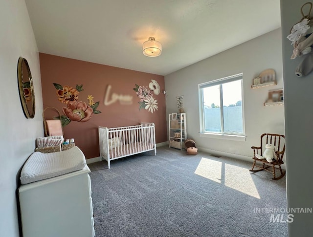 bedroom with a crib and dark colored carpet