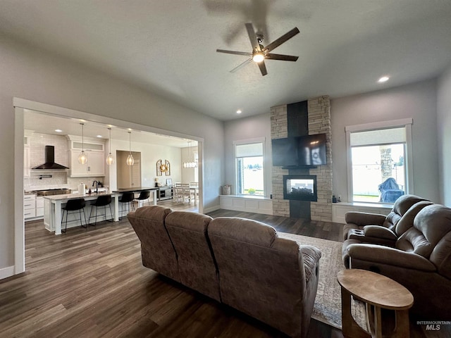 living room featuring a stone fireplace, ceiling fan, and dark hardwood / wood-style floors