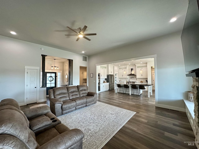 living room with dark hardwood / wood-style flooring and ceiling fan with notable chandelier