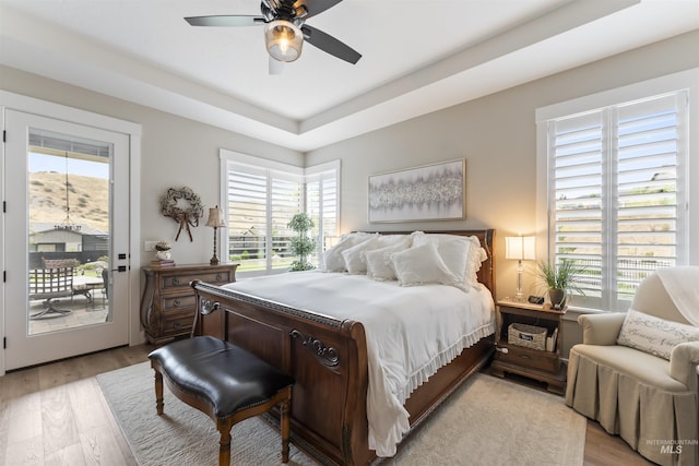 bedroom featuring access to exterior, multiple windows, and light wood finished floors