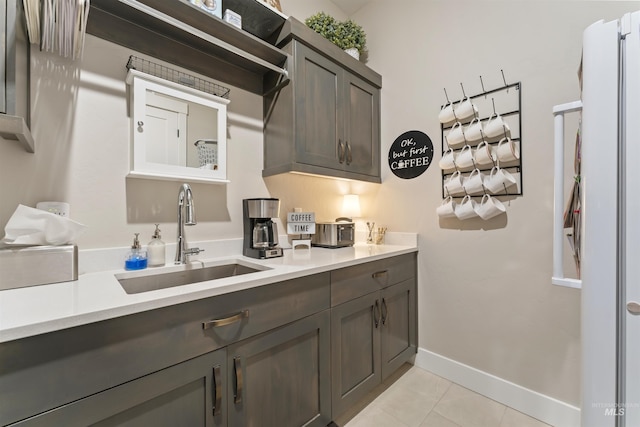 kitchen featuring dark brown cabinets, light countertops, a sink, and light tile patterned flooring