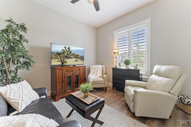 living room with a ceiling fan, baseboards, and wood finished floors