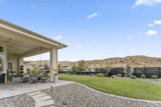 view of yard featuring a patio, a fenced backyard, and a mountain view