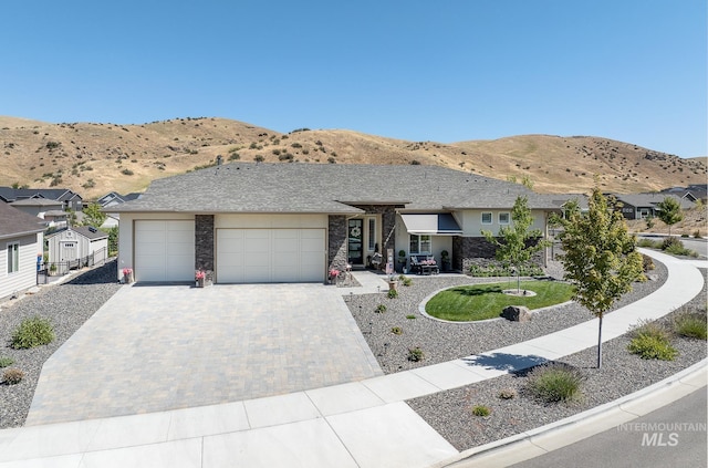 single story home with a garage, a residential view, decorative driveway, and a mountain view