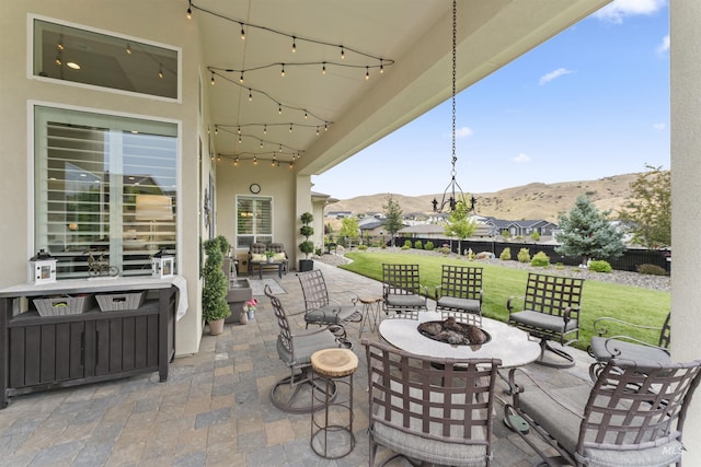 view of patio with an outdoor fire pit, fence, and a mountain view