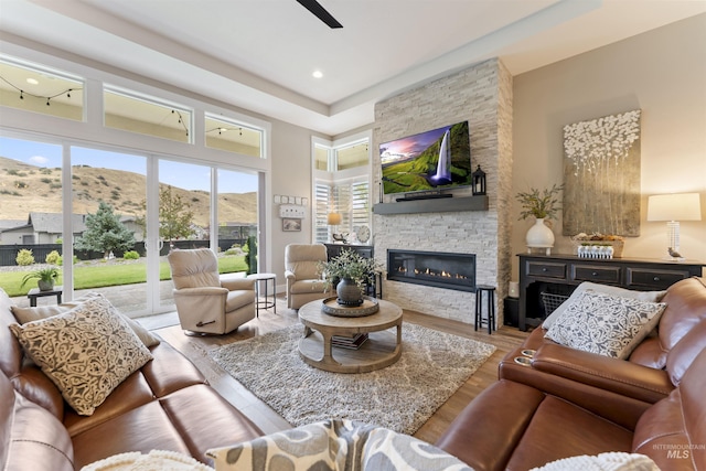 living room with light wood-style floors, a fireplace, and ceiling fan