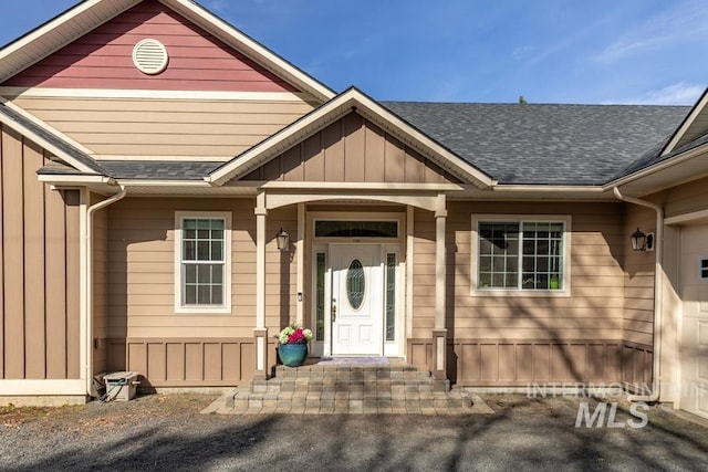 doorway to property with board and batten siding and a shingled roof
