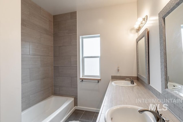 bathroom featuring a bathing tub, tile patterned floors, a sink, and baseboards