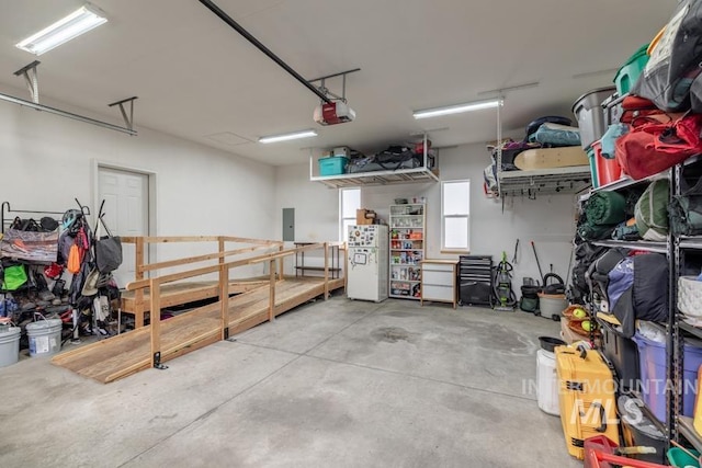 garage with freestanding refrigerator, a garage door opener, and electric panel
