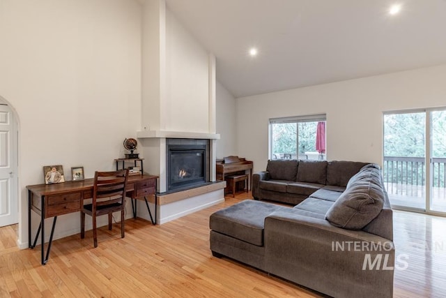 living room featuring light wood finished floors, recessed lighting, high vaulted ceiling, and a glass covered fireplace