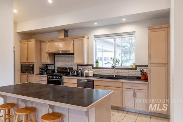 kitchen featuring gas range, built in microwave, a sink, and light brown cabinets