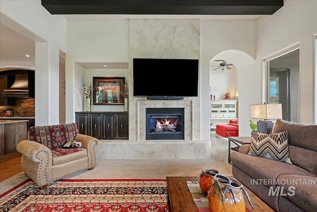 1480 N Colline Bello, Eagle, ID 83616 - living area with a ceiling fan, a tiled fireplace, wood finished floors, a towering ceiling, and arched walkways