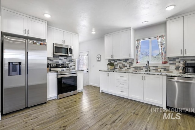 1930 Poplar Ave, Twin Falls, ID 83301 - kitchen featuring stainless steel appliances, light wood-style flooring, tasteful backsplash, white cabinetry, and recessed lighting