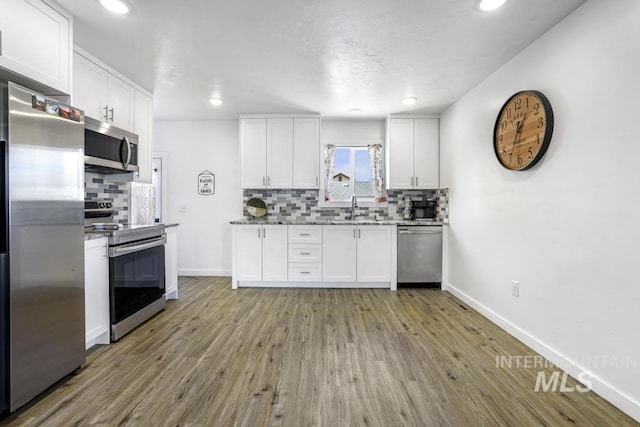 1930 Poplar Ave, Twin Falls, ID 83301 - kitchen featuring appliances with stainless steel finishes, decorative backsplash, white cabinetry, light wood-type flooring, and recessed lighting