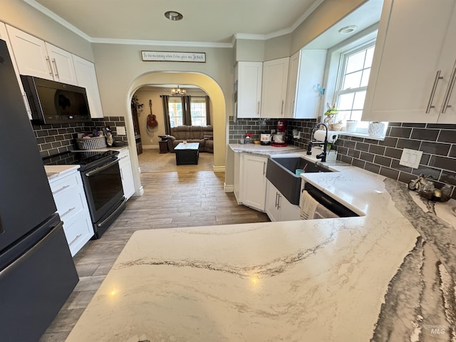 1128 30th St, Lewiston, ID 83501 - kitchen with black appliances, arched walkways, light stone counters, decorative backsplash, and plenty of natural light
