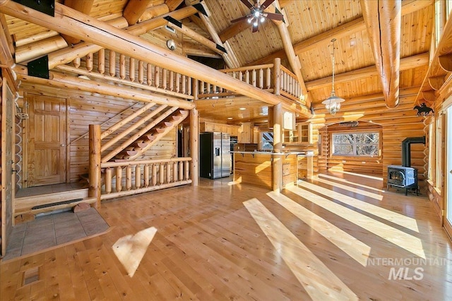 unfurnished living room featuring a wood stove, light hardwood / wood-style floors, wooden ceiling, high vaulted ceiling, and beam ceiling