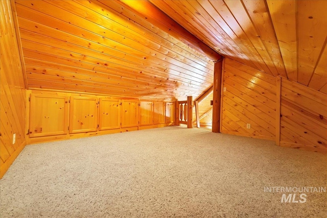 additional living space with carpet, lofted ceiling, wooden walls, and wooden ceiling