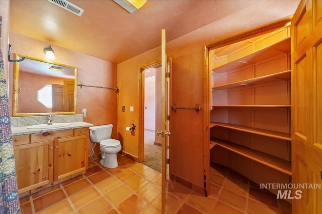 bathroom featuring vanity, tile patterned flooring, and toilet