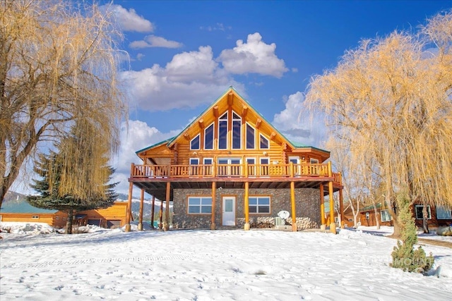 snow covered rear of property with a deck