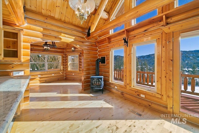 exercise room with a mountain view, light wood-type flooring, a wood stove, wooden ceiling, and high vaulted ceiling