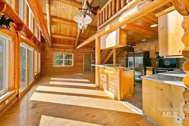 interior space featuring stainless steel fridge, kitchen peninsula, hanging light fixtures, wood ceiling, and beam ceiling