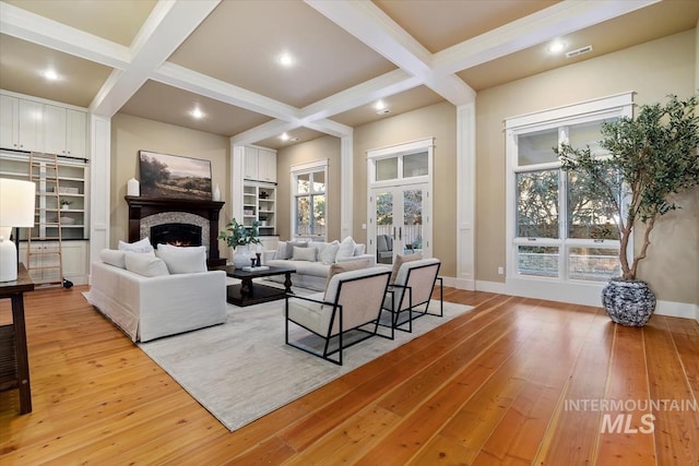 living room featuring coffered ceiling, light hardwood / wood-style flooring, french doors, and beamed ceiling