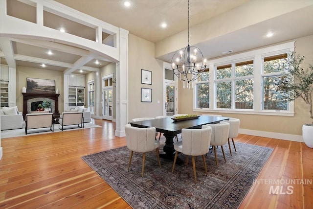 dining area with a notable chandelier, beam ceiling, and light hardwood / wood-style flooring