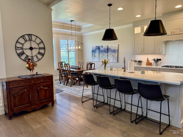 2280 N Burnam Ave, Star, ID 83669 - kitchen featuring ornamental molding, gas stovetop, light wood-type flooring, a breakfast bar area, and a raised ceiling