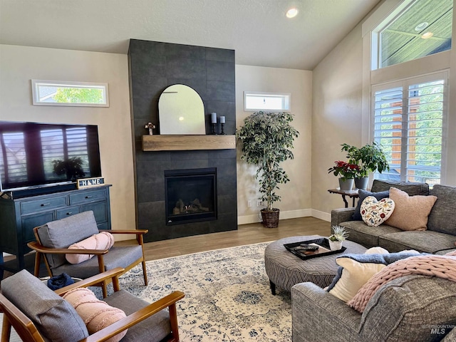 2280 N Burnam Ave, Star, ID 83669 - living room with healthy amount of natural light, a tiled fireplace, wood finished floors, lofted ceiling, and baseboards