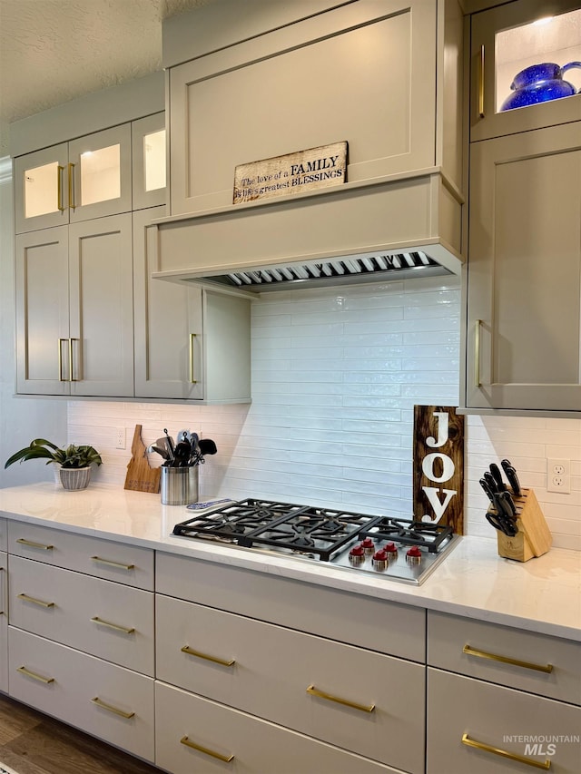 2280 N Burnam Ave, Star, ID 83669 - kitchen featuring stainless steel gas stovetop, decorative backsplash, custom range hood, glass insert cabinets, and light stone counters