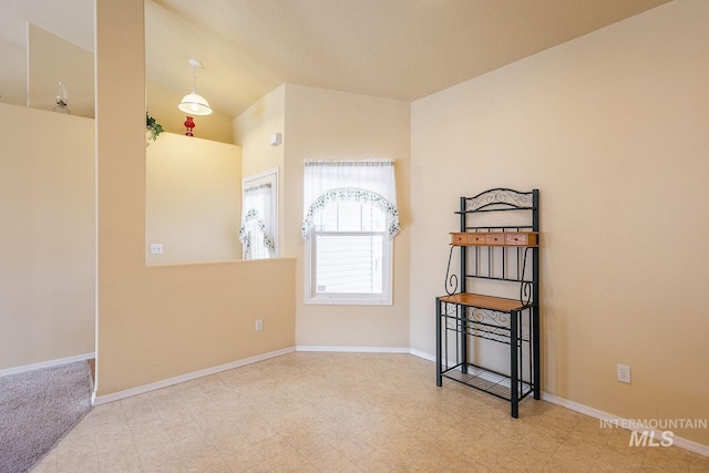 empty room with vaulted ceiling, baseboards, and tile patterned floors