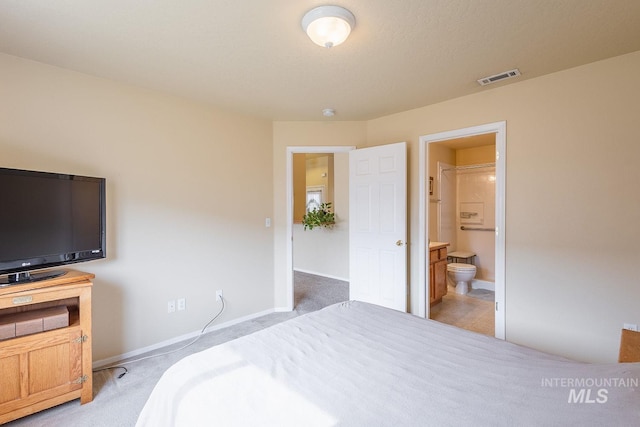 bedroom featuring light colored carpet, baseboards, visible vents, and ensuite bath